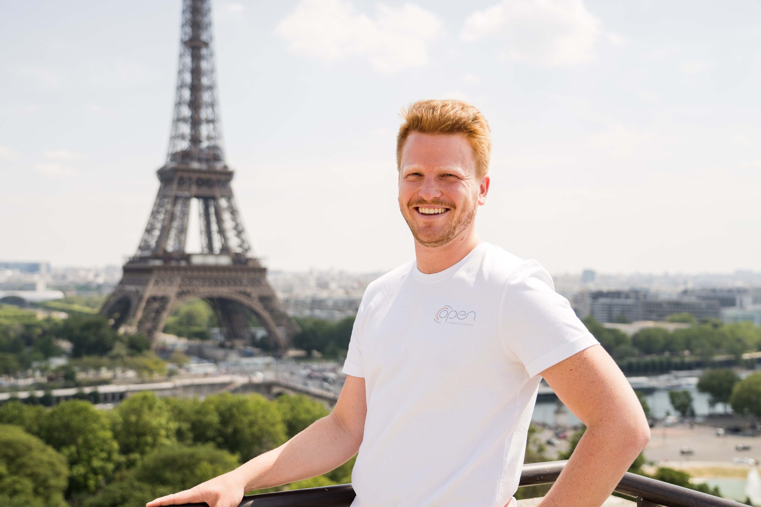 Un homme pose devant la tour Eiffel.
