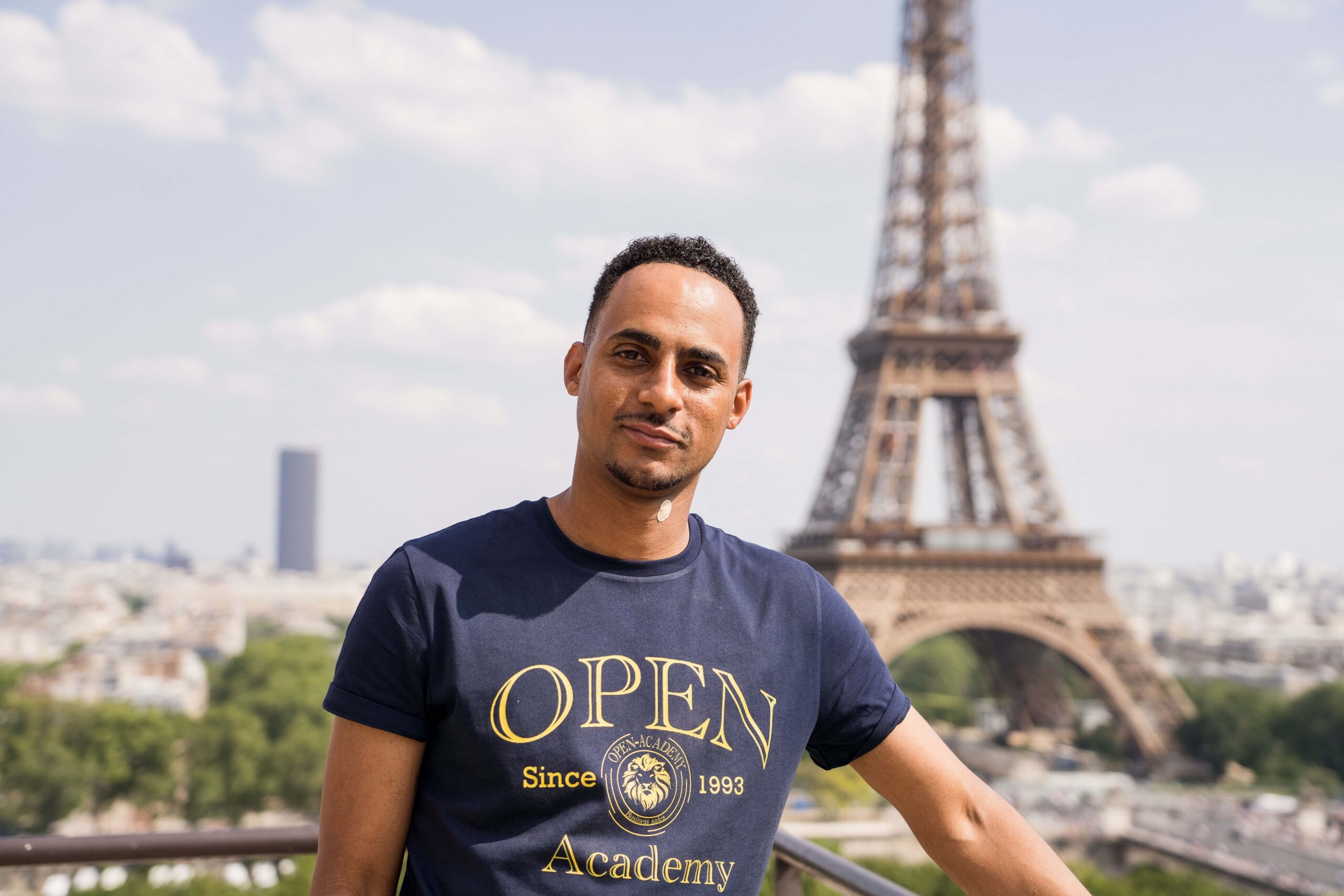 Homme en tee shirt bleu devant la tour Eiffel