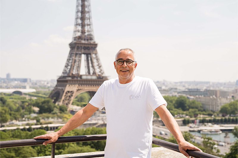 Un petit homme à lunette avec un fond Tour Eiffel