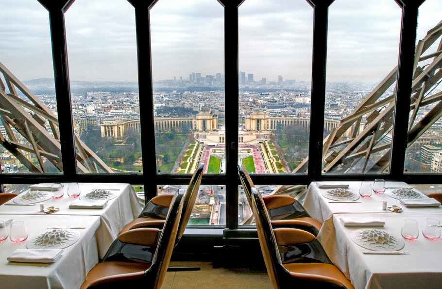Vue de la Tour Eiffel depuis un restaurant, tables et chaises, cadre élégant.