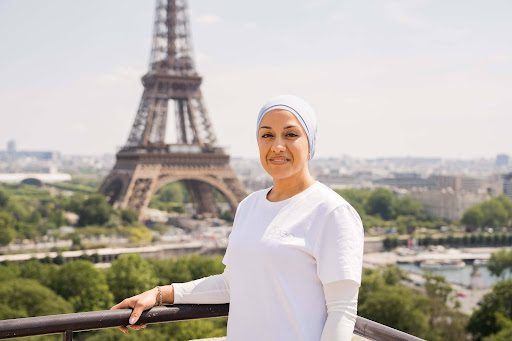 Une femme souriante debout devant la Tour Eiffel