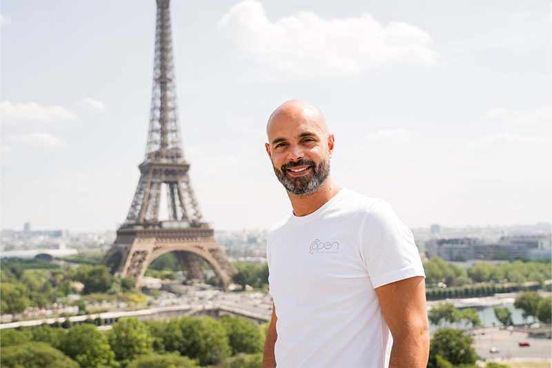 Un homme grand chauve devant la Tour Eiffel