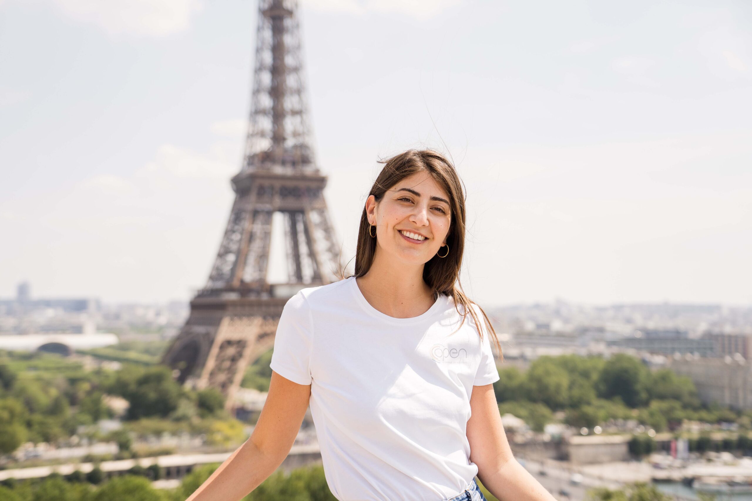 Une grande femme pose devant la tour Eiffel