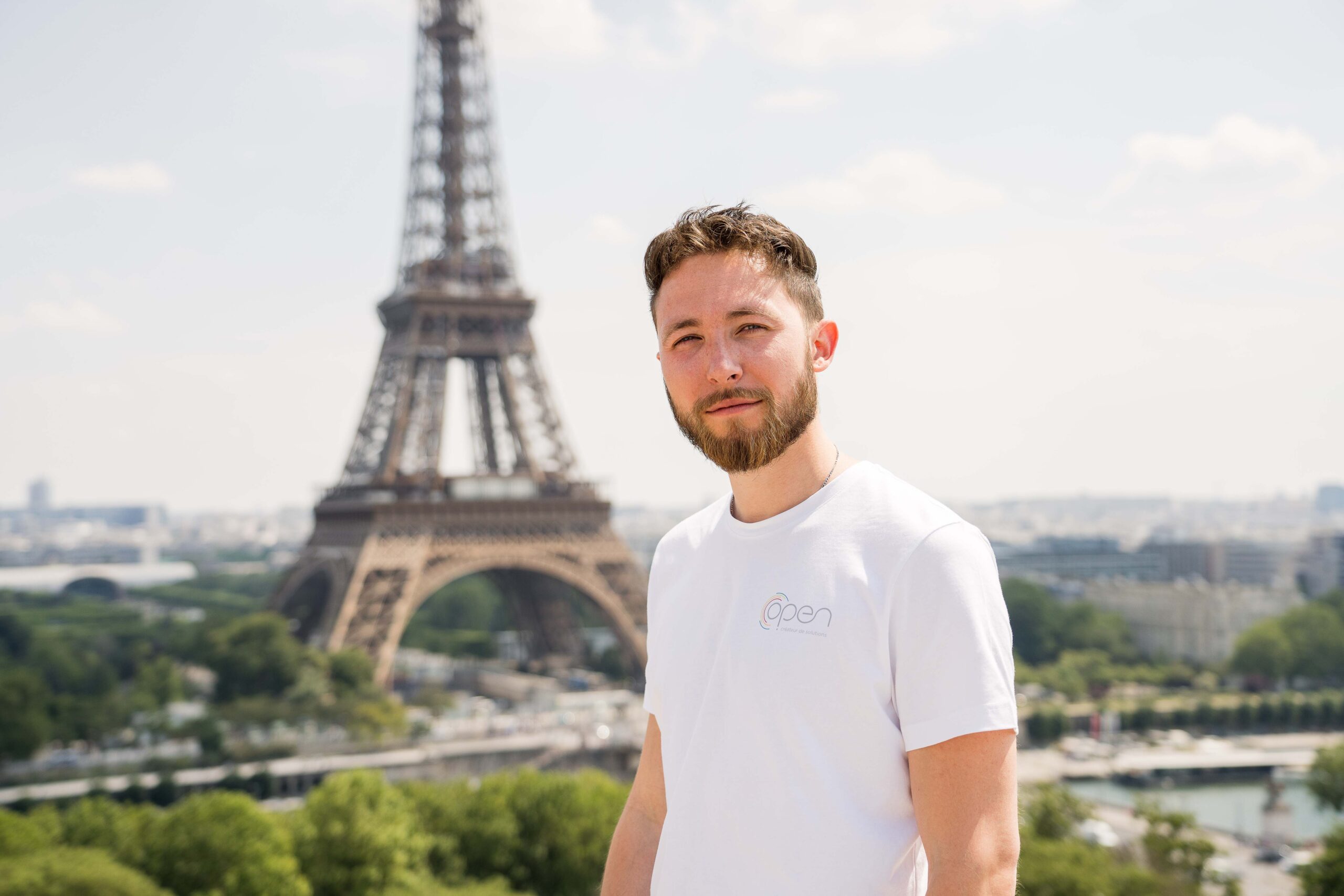 Un jeune homme debout devant la tour Eiffel.