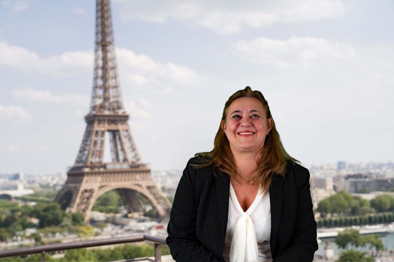 Une femme en costume d'affaires assise devant la tour Eiffel.